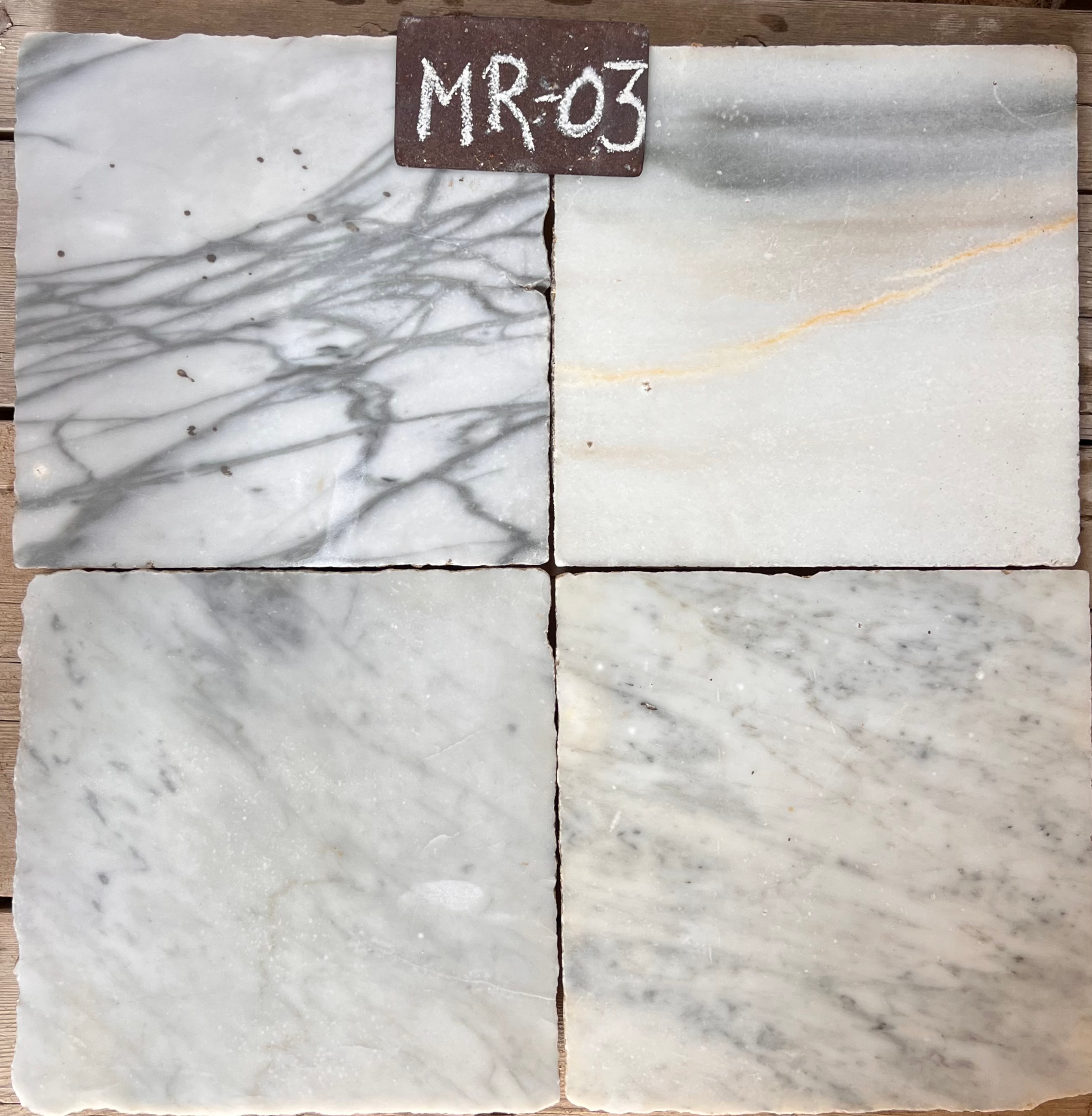 Cuatro piezas de mármol recuperado en blanco con venas grises y una con tonos beige, formato 28x28 cm