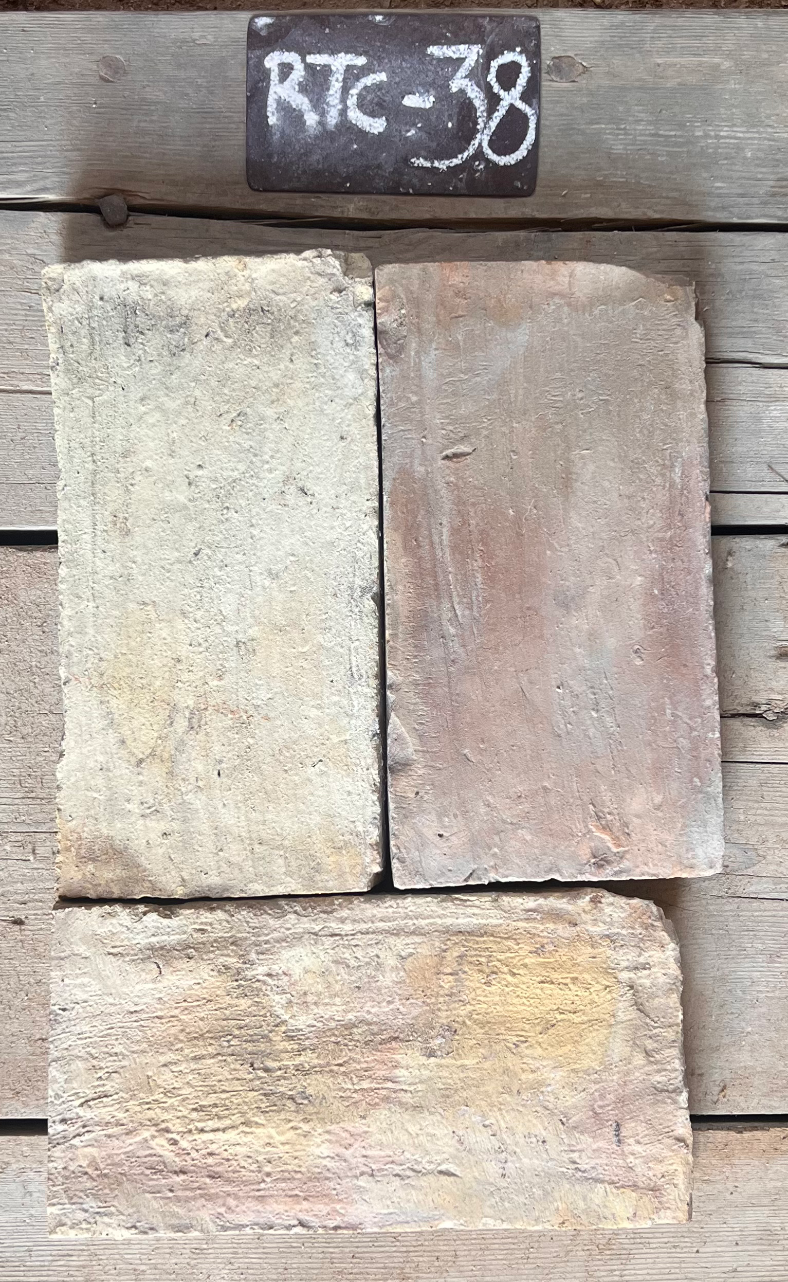 Tres piezas de barro cocido recuperado mostrando variación entre gris claro y terracota rosado, formato alargado