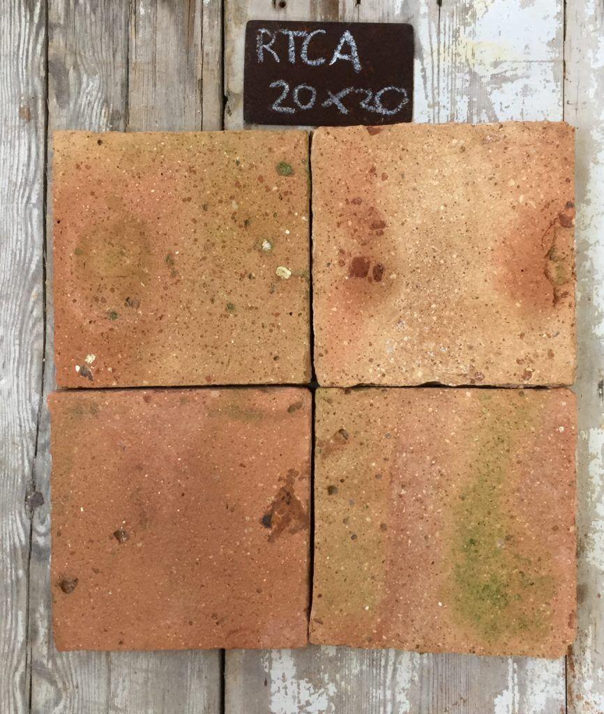 Cuatro piezas de barro cocido recuperado en terracota salmón con manchas de color verde natural, formato 20x20 cm