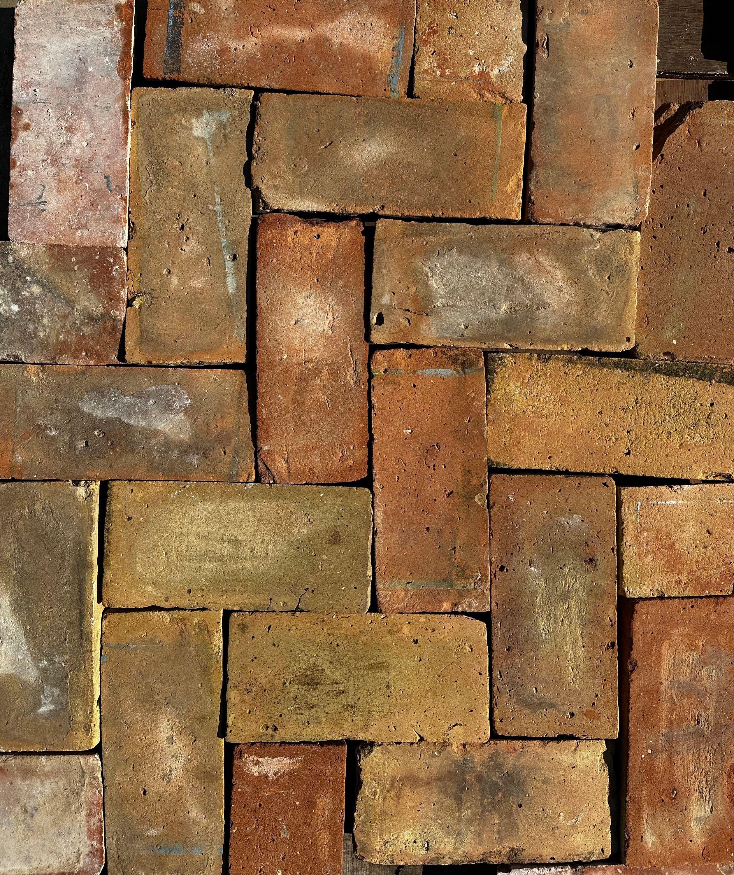 Conjunto de piezas de barro cocido recuperado apiladas mostrando mezcla de terracota, ocre y gris, formato 30x13 cm