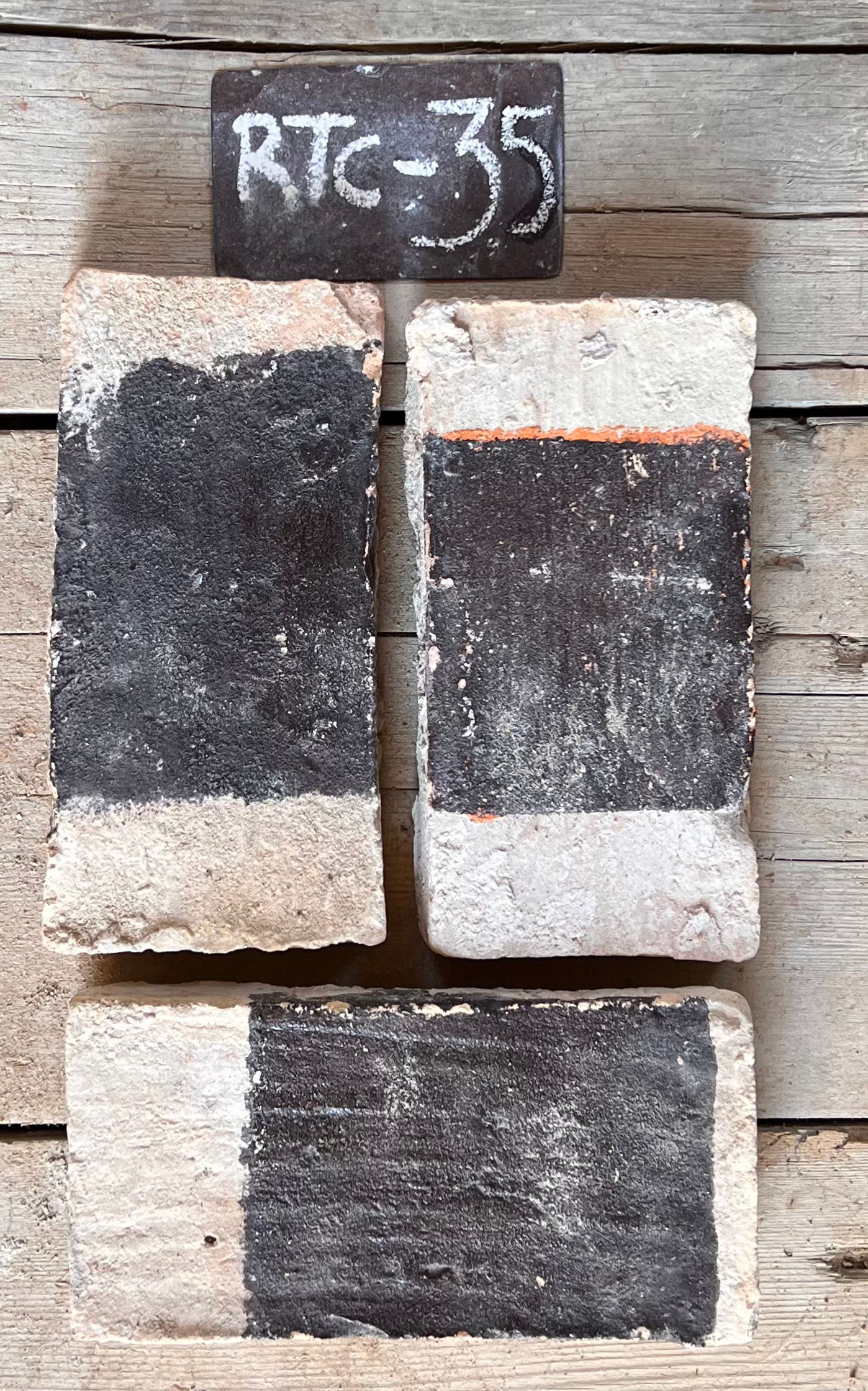 Dos piezas de barro cocido recuperado con color negro en la parte superior y terracota naranja en la inferior, formato 24x12 cm